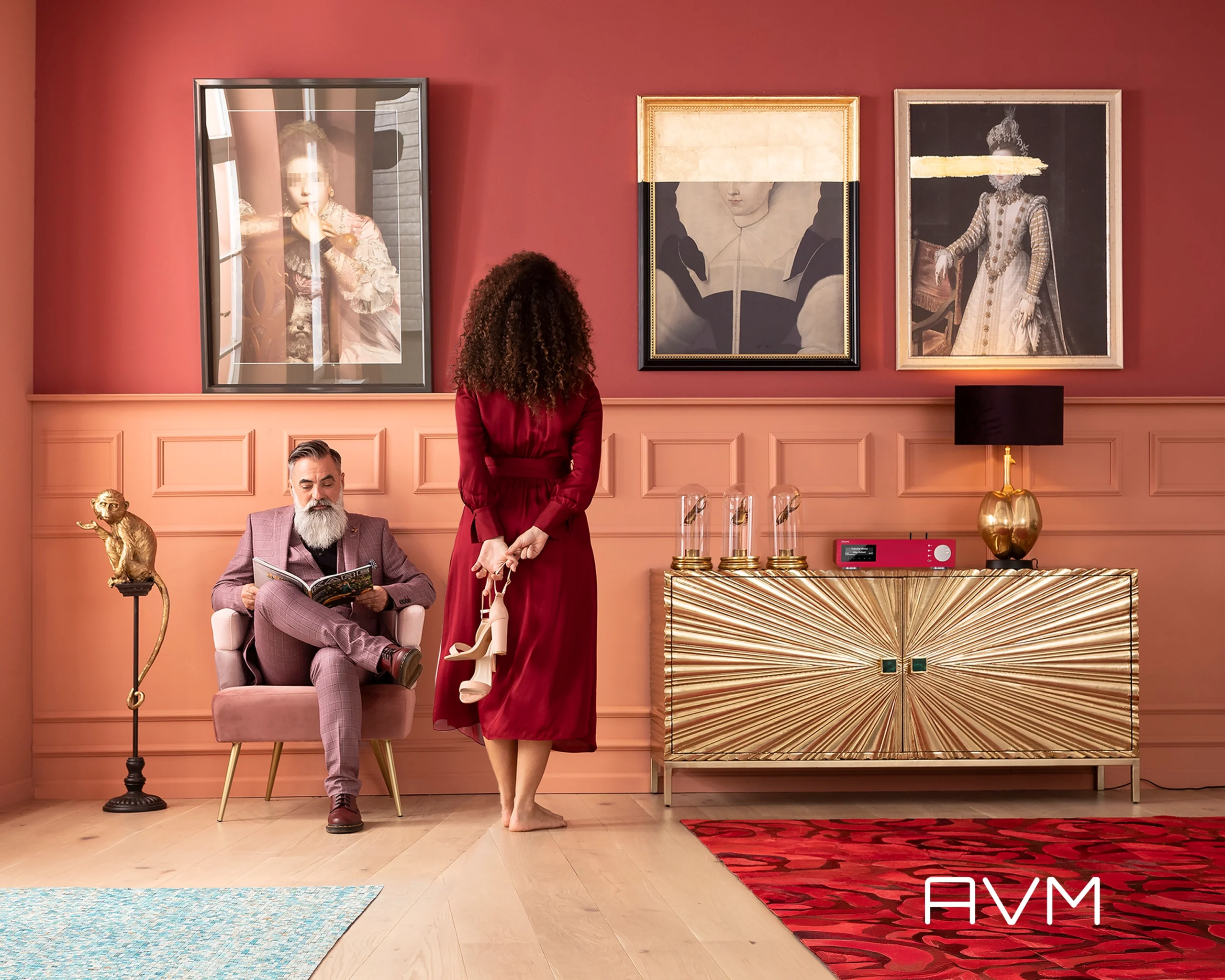 A rose-pink drawing room with AVM electronics on a gold sunburst cabinet, framed portraits above