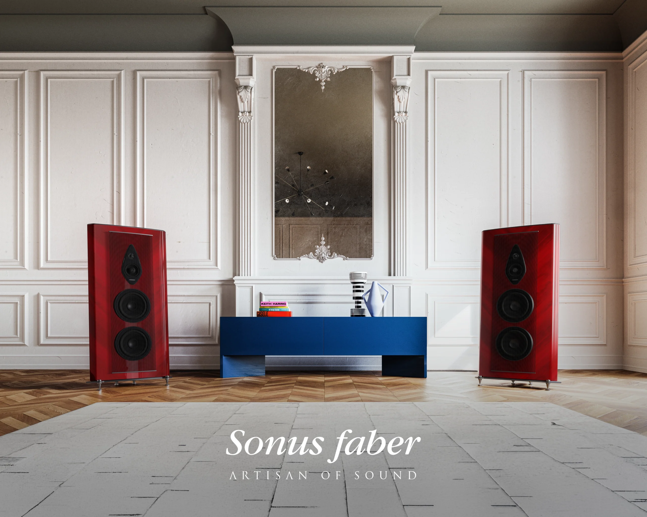 A pair of red lacquered Sonus Faber Stradivari loudspeakers flanking a blue sideboard in a white panelled room with a tall gilt mirror.