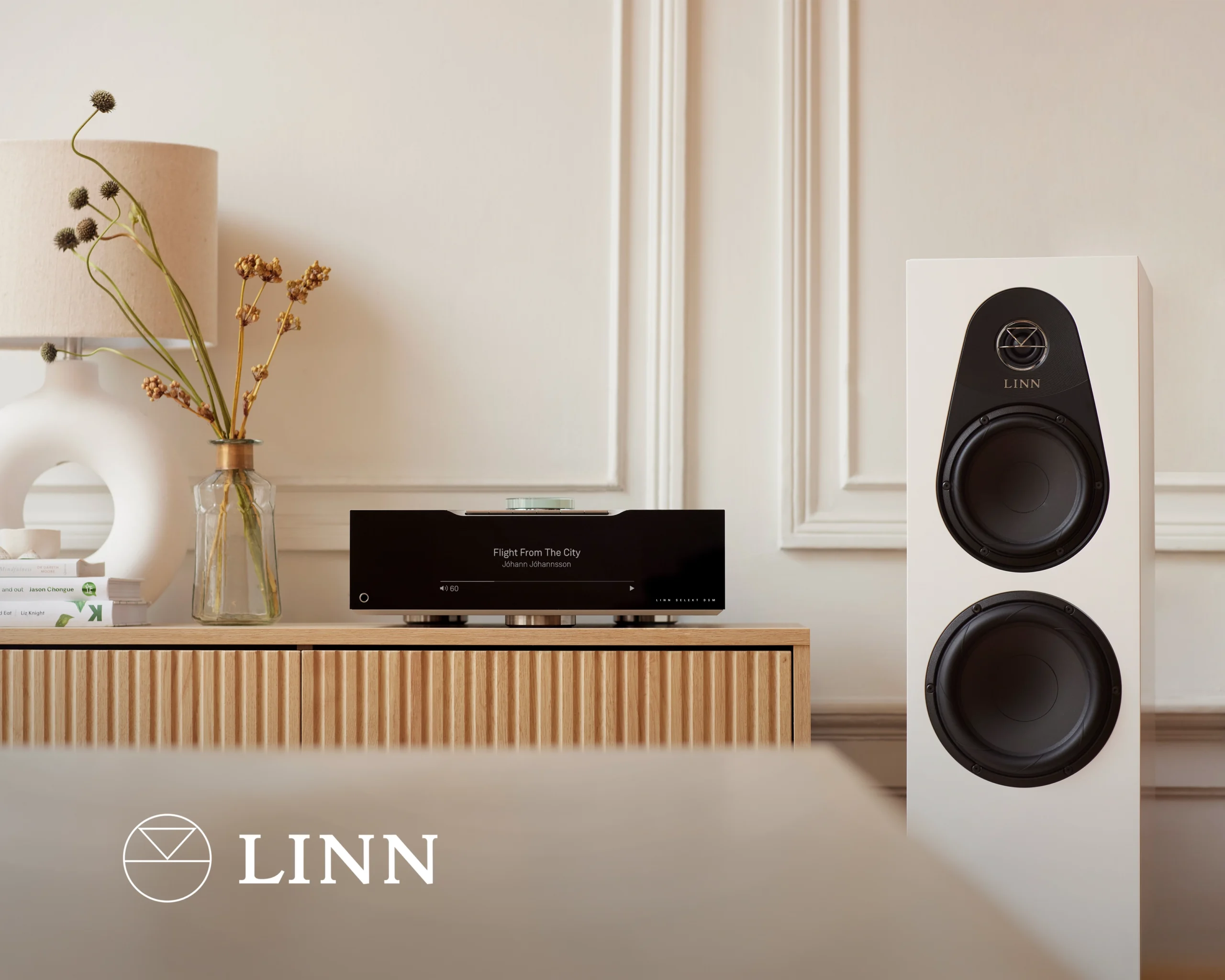 A Linn music system on an oak sideboard, its display showing Flight From The City, with a white Linn floorstanding loudspeaker alongside.