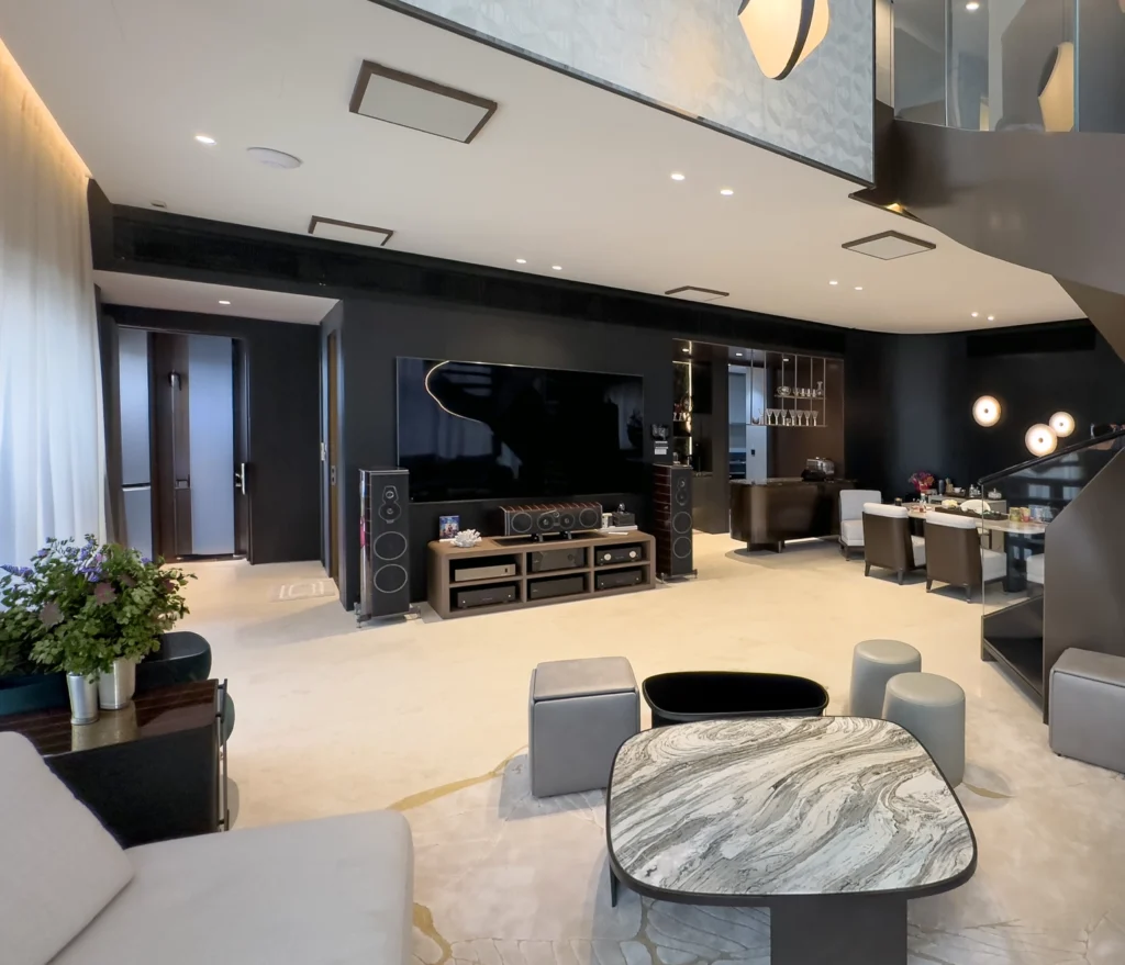 A Sonus Faber Amati 5.2.4 home theatre in a double-height living room, with a large screen and Amati floorstanders set against a dark feature wall.