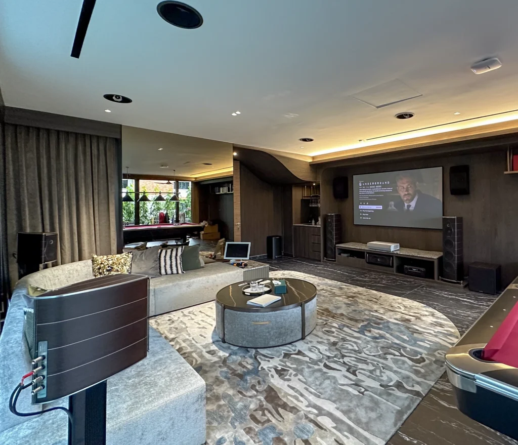 A Sonus Faber Olympica Nova home theatre and karaoke room, with a projection screen and floorstanding speakers alongside a pool table.