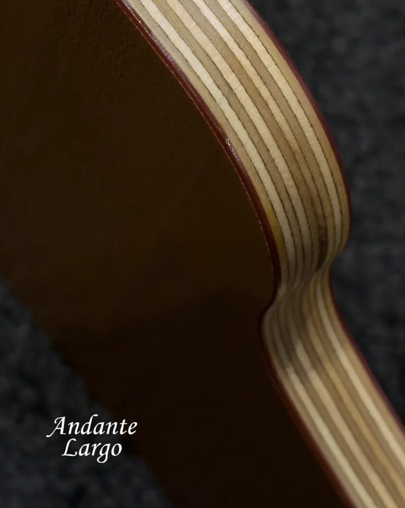 Close-up of the layered plywood edge of an Andante Largo shelf with a dark leather-like top.