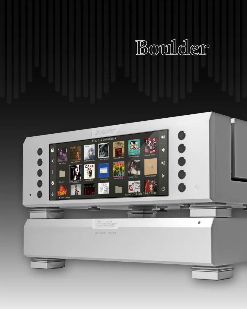Boulder silver digital converter with a colour touchscreen, stacked on a power amplifier against a dark background.