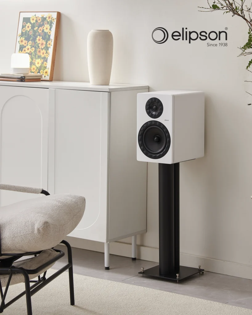 White Elipson bookshelf speaker on a black stand beside a white cabinet in a light room.