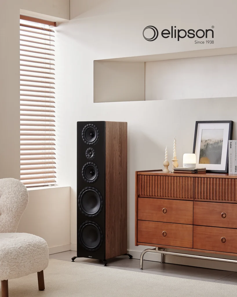 Tall Elipson floorstanding speaker with a walnut side and black front baffle beside a wooden sideboard.