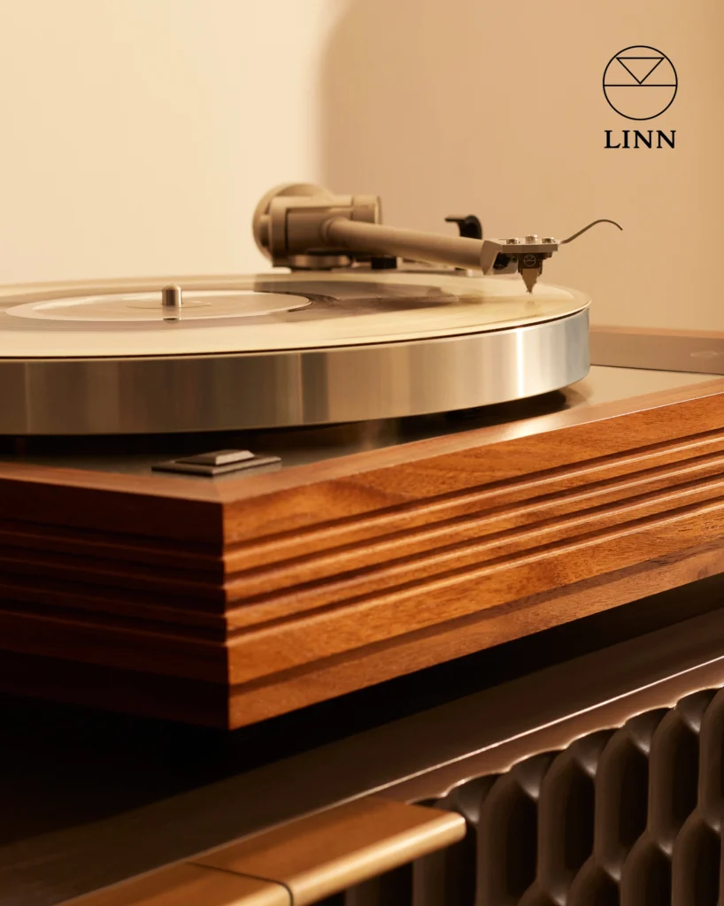Linn turntable with a walnut plinth and a tonearm over the platter, in warm light.