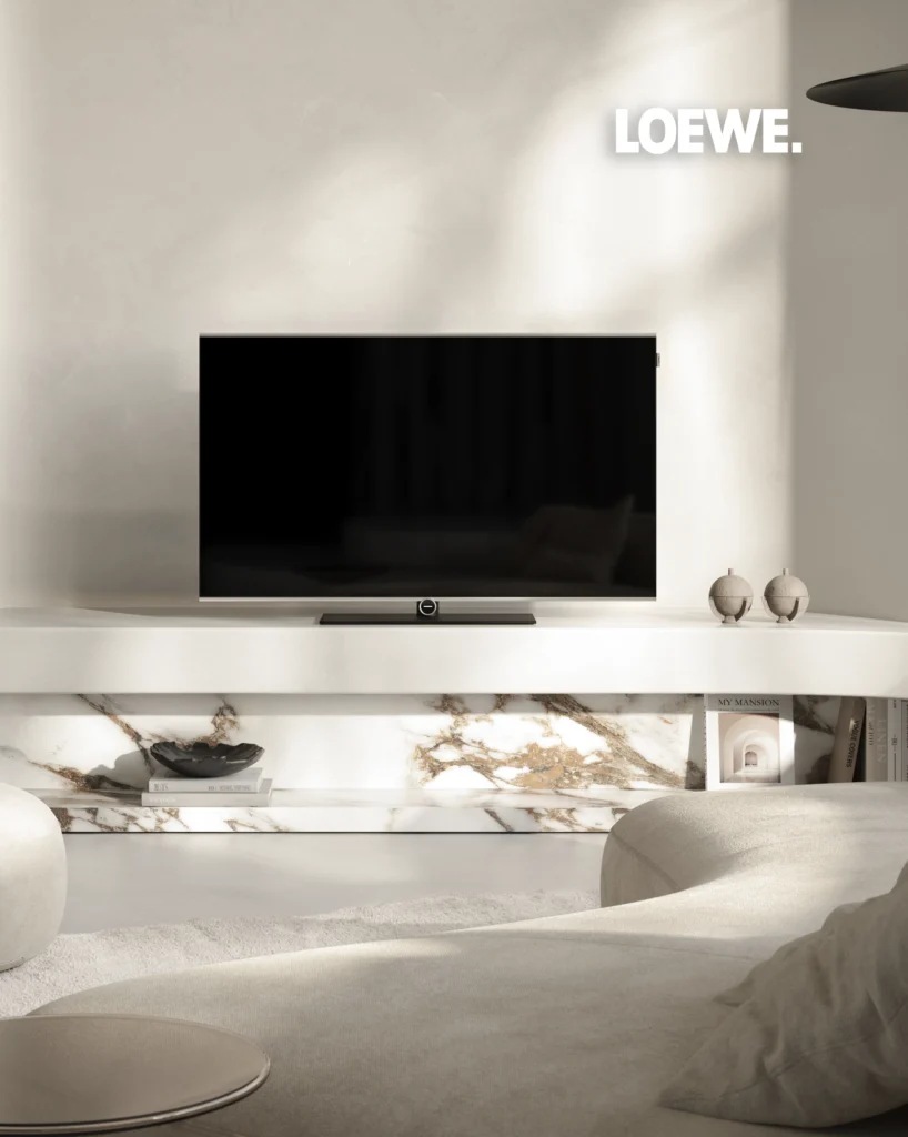 A Loewe television on a marble-topped console, with two sculptural sphere ornaments beside it in a light interior.