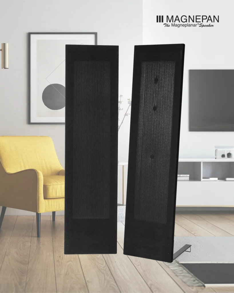 Pair of black Magnepan panel speakers in a bright living room beside a yellow armchair.