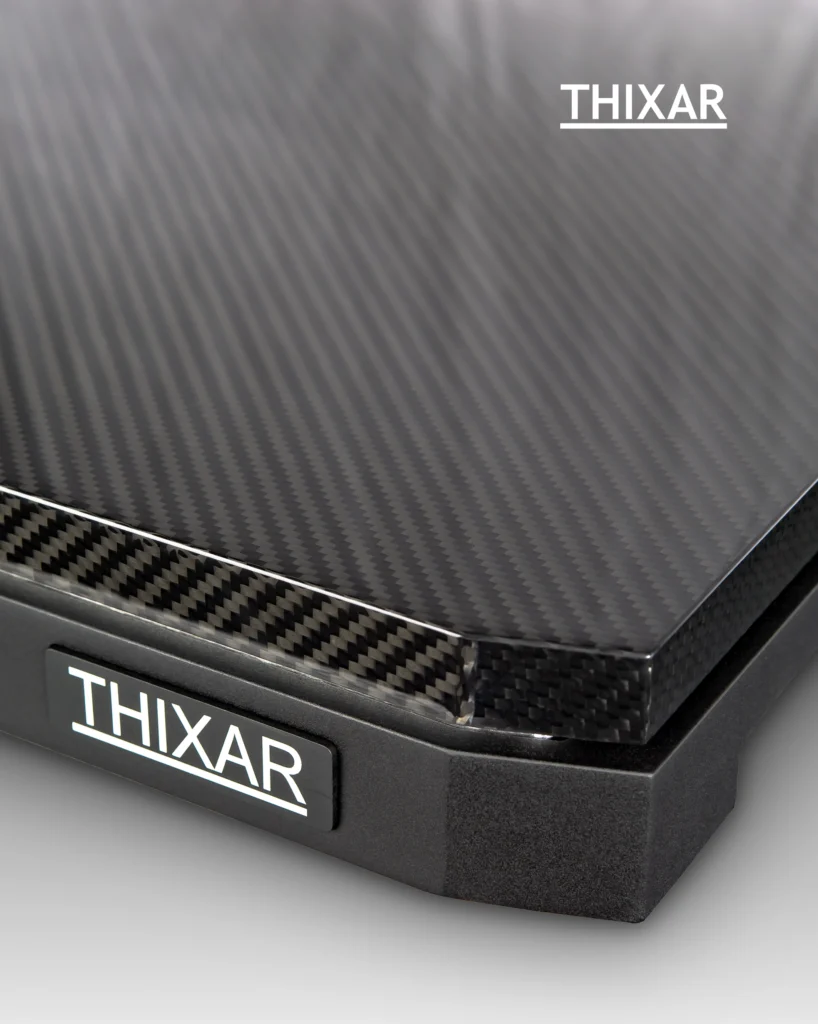 Corner of a Thixar isolation platform with a carbon fibre top and a black base carrying the Thixar badge.
