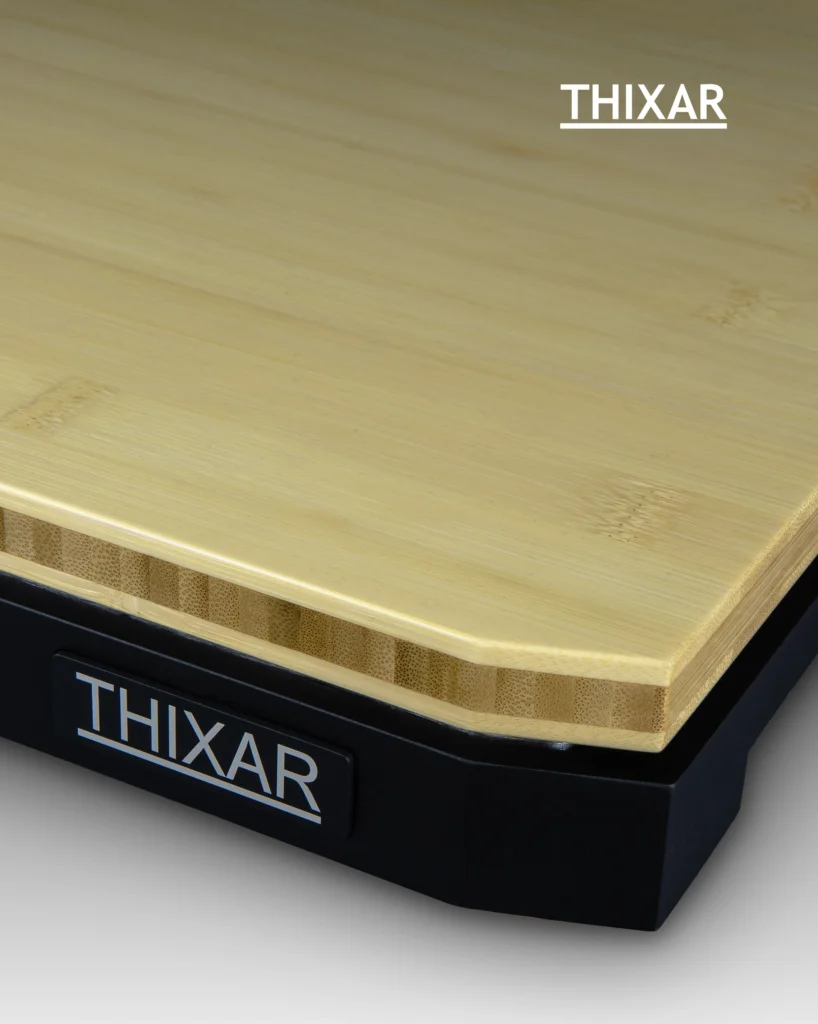Corner of a Thixar isolation platform with a bamboo top and a black base carrying the Thixar badge.