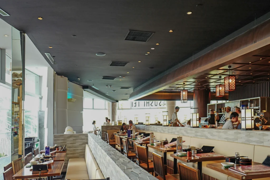 Dining room of the Sushi Tei restaurant with recessed ceiling lights and booth seating along one wall