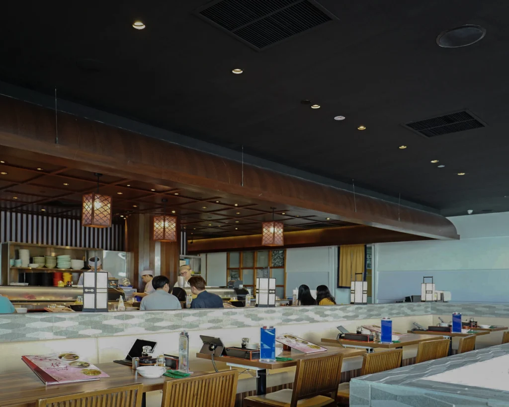Sushi bar and booth seating beneath a timber ceiling canopy with lantern pendants