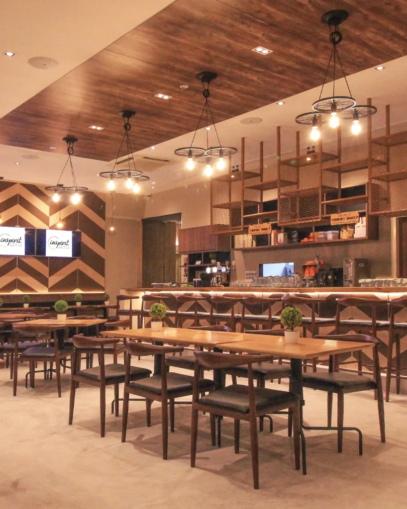 A restaurant interior with timber tables, leather chairs, pendant lights and a long bar counter