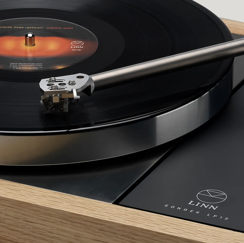 A Linn Sondek LP12 turntable in close view, its tonearm and cartridge tracking a Linn Records LP on the platter.