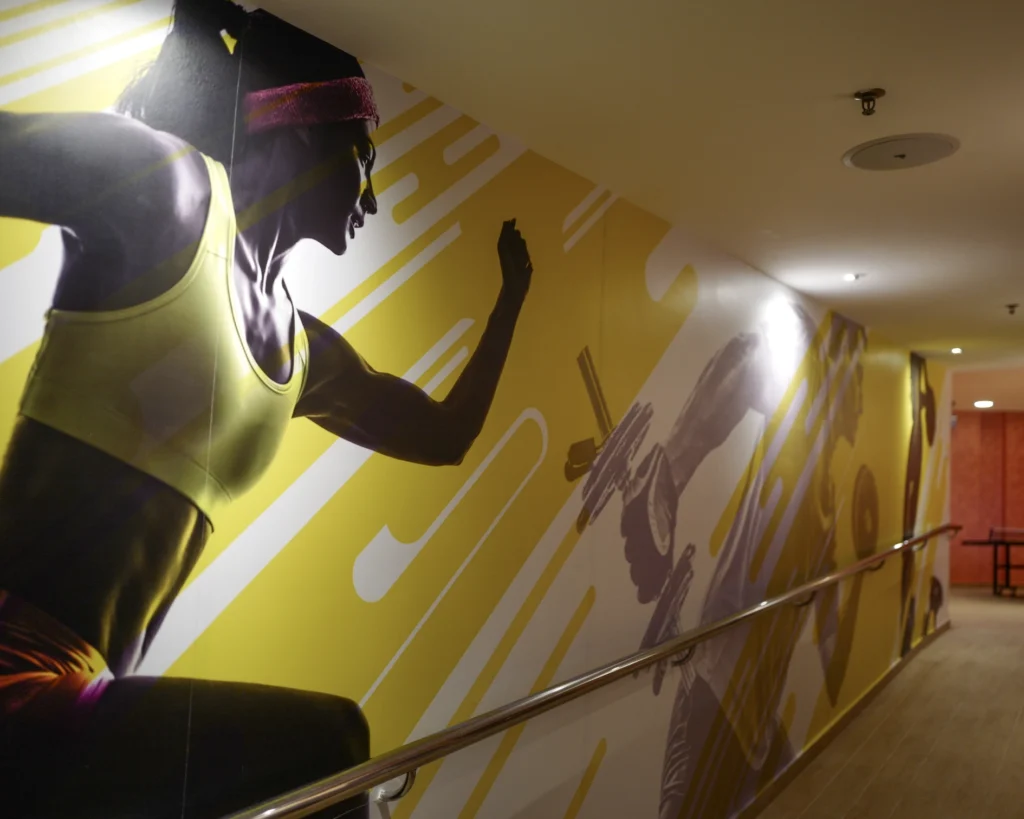 Ceiling speaker above a corridor wall printed with a large graphic of a runner