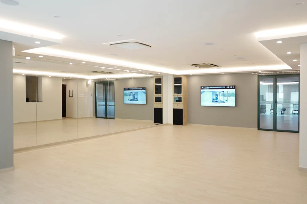Condo function room with a mirrored wall, two wall-mounted screens and recessed ceiling speakers