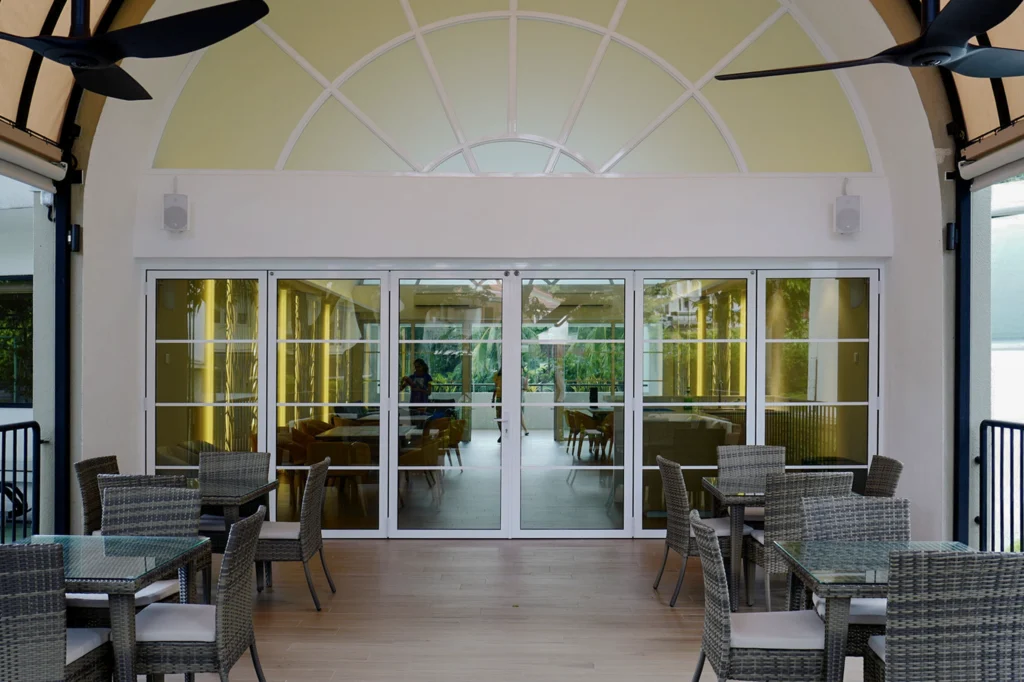 Clubhouse dining area with wall-mounted speakers either side of a glass door wall under an arched window