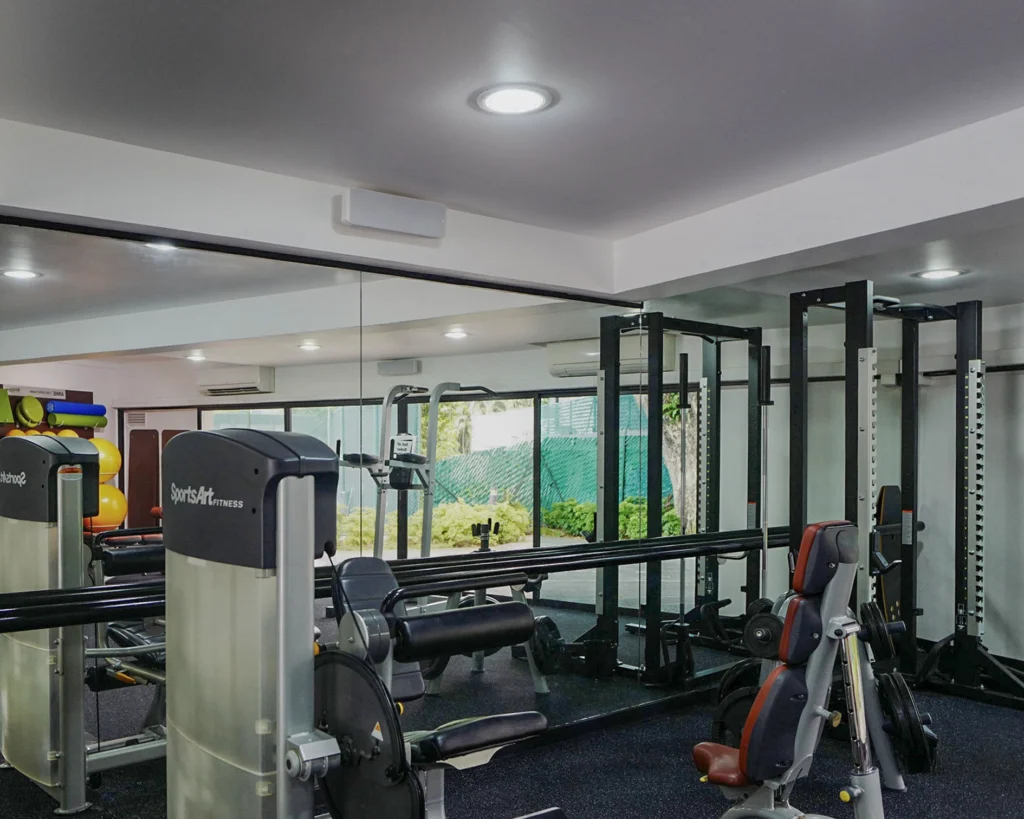 Condominium gym with weight racks, a mirrored wall and a speaker mounted high on the wall
