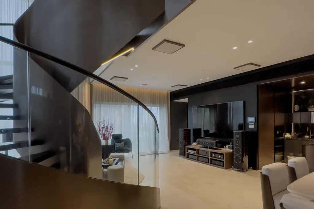 Sonus Faber Amati floorstanding speakers either side of a large TV in a double-height living room with a spiral staircase