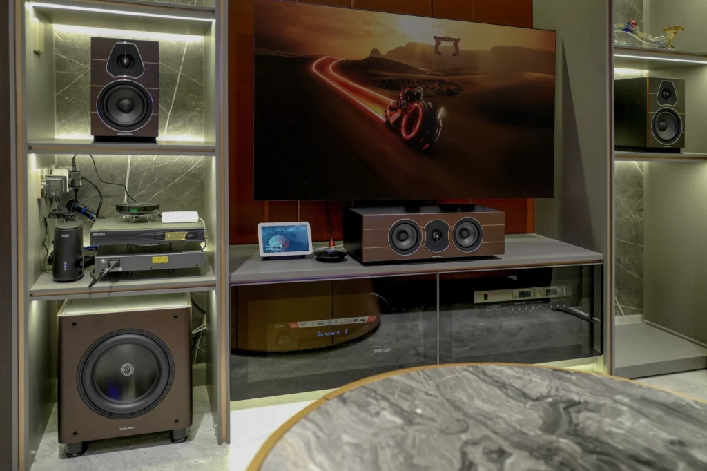 Sonus Faber Lumina bookshelf speakers and a Lumina centre speaker set into a lit joinery wall, with a subwoofer below and a wall-mounted television.