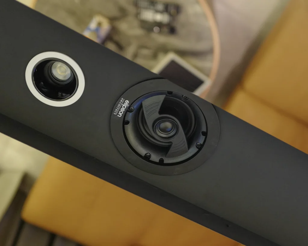 Close-up of an Elipson Architect in-ceiling speaker, flush-mounted in a black ceiling bulkhead beside a downlight.
