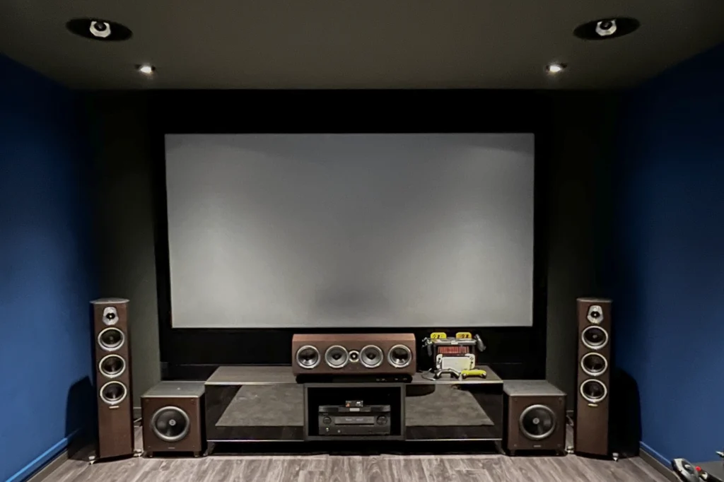 Sonus Faber Sonetto floorstanding and centre speakers around a projection screen in a dark blue home cinema