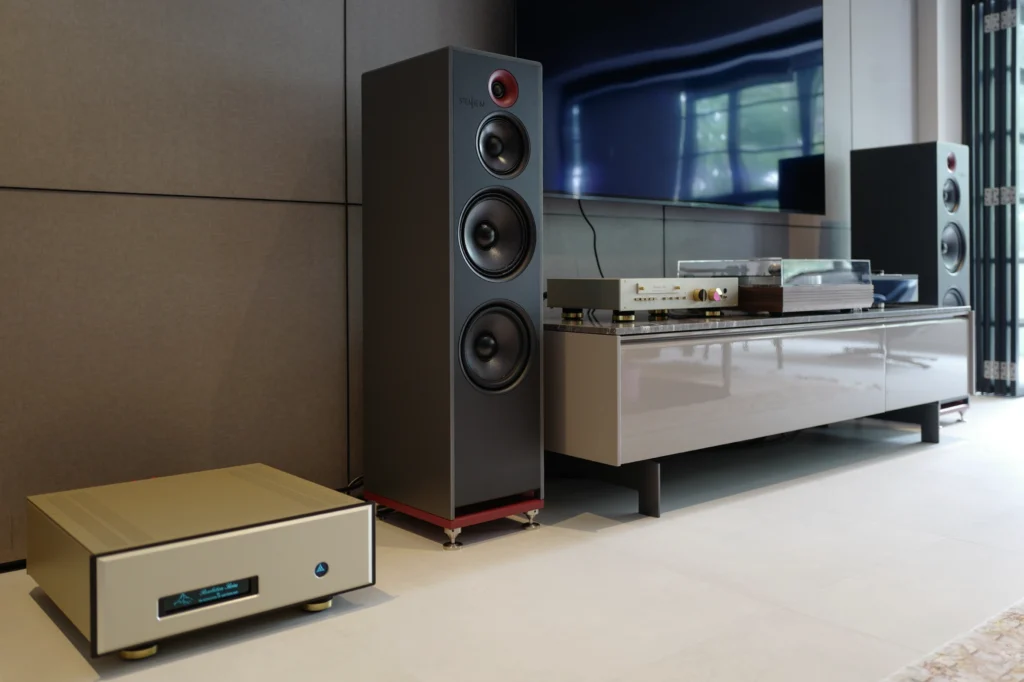 Stenheim floorstanding speaker beside a TV cabinet holding a turntable and gold-fronted electronics