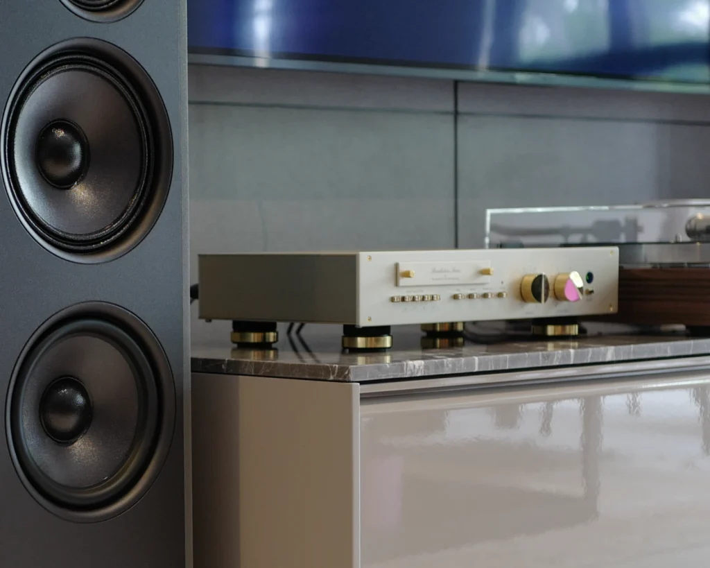 Close-up of a Stenheim speaker's drivers beside a gold-fronted preamplifier on a marble-topped cabinet