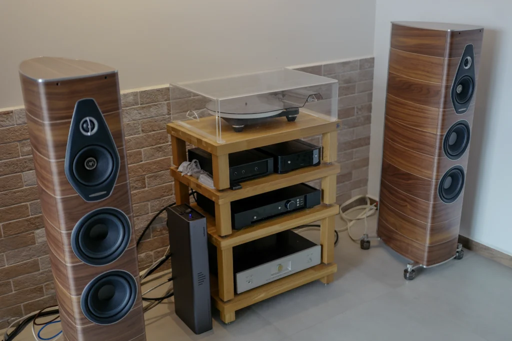Two walnut Sonus Faber Olympica Nova III speakers either side of a timber rack holding a turntable and electronics