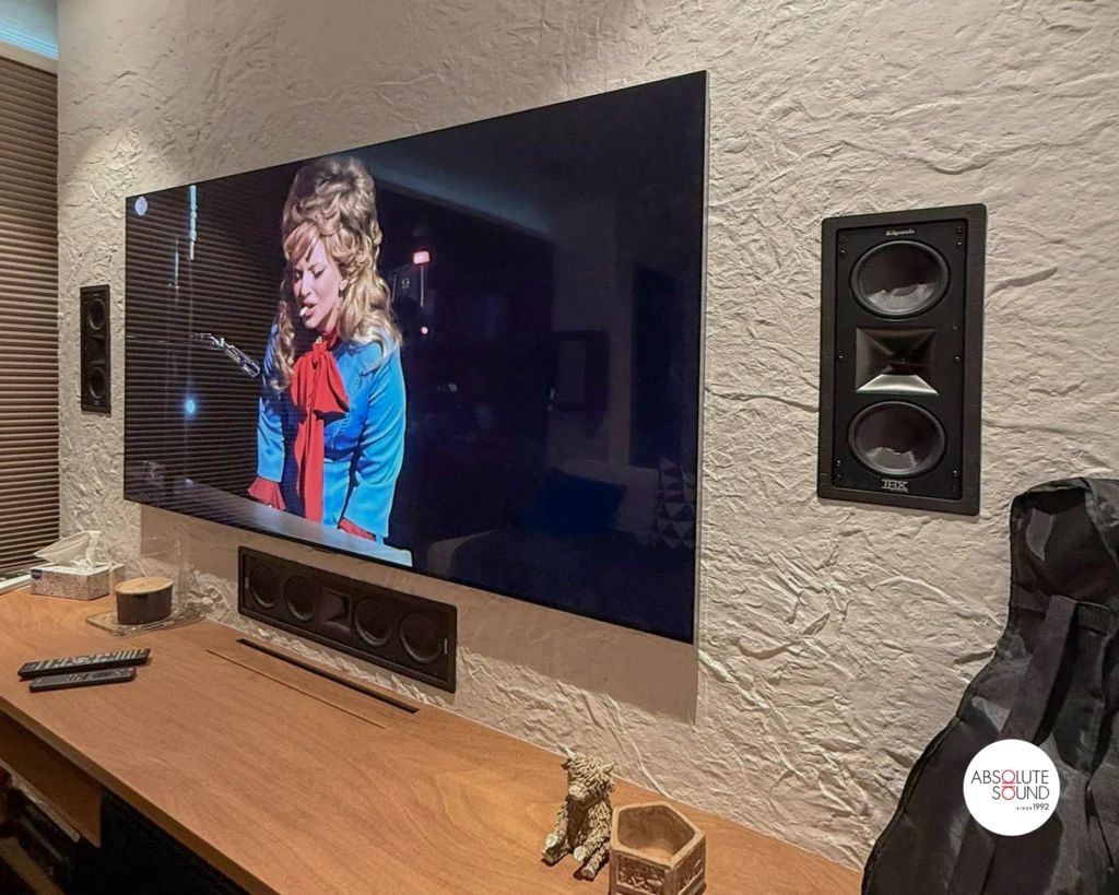 Close-up of the right-hand Klipsch THX-502-L, grille off, showing horn and two woofers, with the centre slot below the TV.