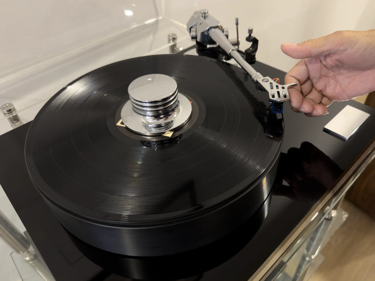 Lowering the tonearm onto a record on a black turntable