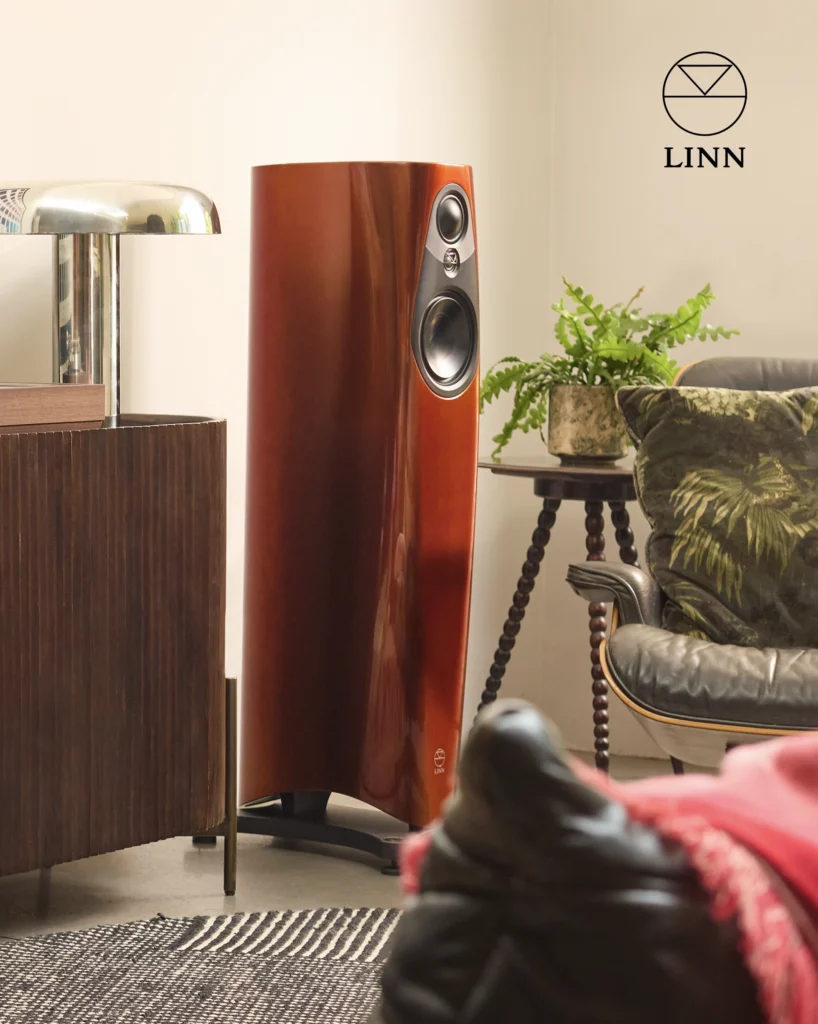 Linn 343 loudspeaker in a gloss wood finish, in a living room beside a lounge chair